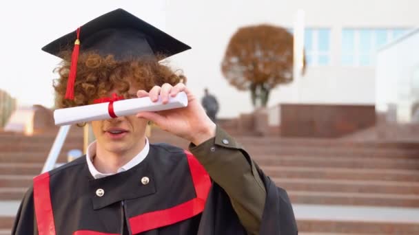 陽気男で卒業式の衣装ショー彼の卒業証書と笑顔でカメラ — ストック動画