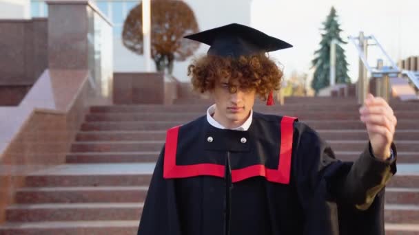 Joven Graduado Divertido Manto Maestros Corrige Sombrero Cabeza — Vídeo de stock