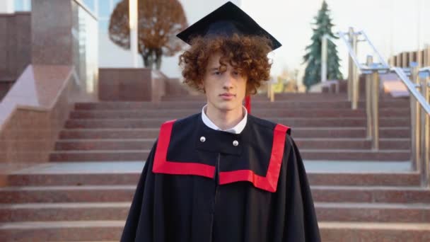 Jeune Diplômé Drôle Dans Manteau Des Maîtres Sourit Caméra — Video