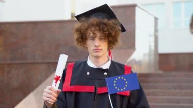 Kıvırcık, komik, gülümseyen bir mezun yüksek lisans eğitimini tamamlama diplomasına sahip.