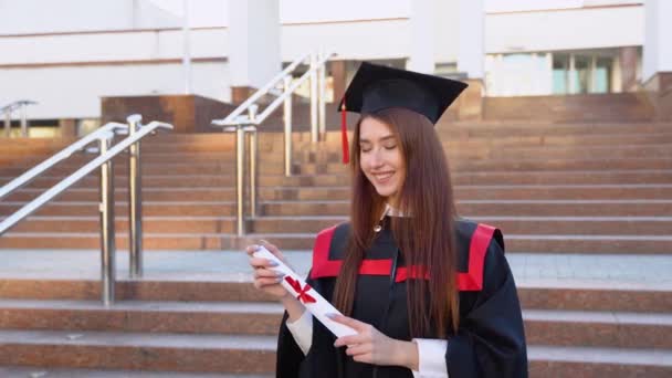 若い女性の専門家は マスターのマントルに立って エレガントに卒業証書を保持します — ストック動画