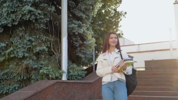 大学やオフィスビルの近くの階段を歩いている若い女の子の学生 本を持って — ストック動画