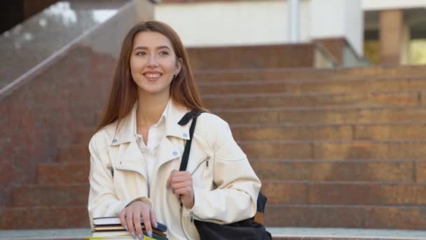 Szczęśliwa Studentka Pozowała Plecakiem Trzymając Książki Uśmiechnięte Patrząc Kamerę Siedzącą — Wideo stockowe