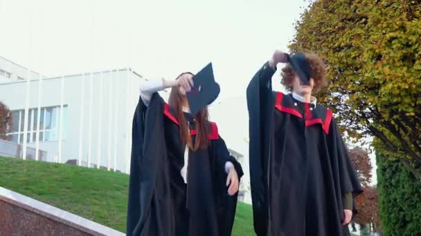 修士課程の男と女の卒業生は主人の帽子を投げます — ストック動画