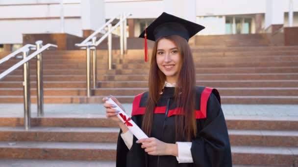 Genç Kız Bir Öğrenci Ustalık Pelerininde Durur Zarifçe Diplomasını Tutar — Stok video