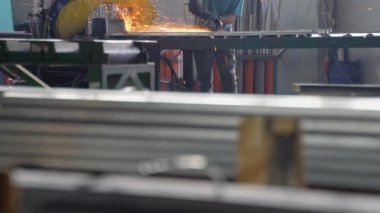Açısal öğütme makinesi ve metal boru kullanan bir endüstriyel işçiyle birlikte ağır bir mühendislik fabrikasının içi..