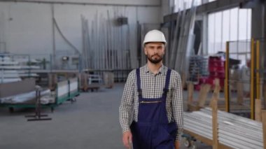 Güvenlik üniforması giyen profesyonel mühendis kameraya doğru geliyor ve gülümsüyor..