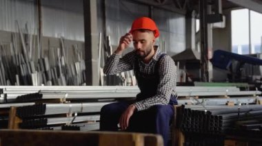 Büyük bir metal fabrikasında kask takan genç bir işçi. Shiftman bitmiş ürün deposunda.