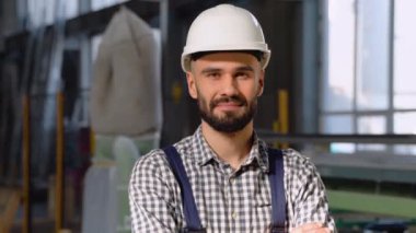 Fabrikada çalışan koruyucu kasklı genç adam. Fabrikadaki işçinin portresi.