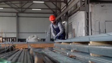 Büyük bir metal fabrikasında kask takan genç bir işçi. Shiftman bitmiş ürün deposunda..