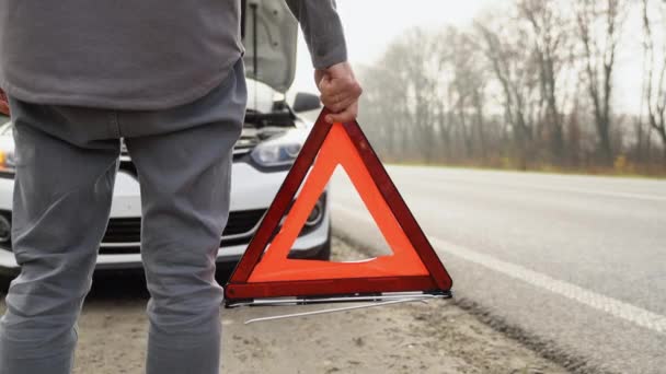 霧の多い道路に赤い三角形の注意標識を持つ男 旅行の概念 — ストック動画