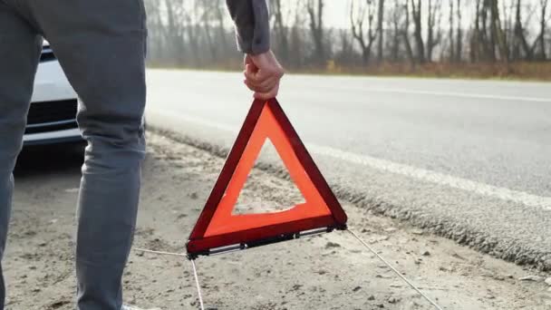 男は壊れた車の近くの霧の道に三角形の注意標識を置く — ストック動画