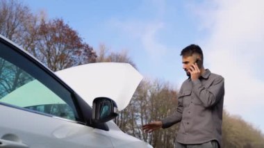 Üzgün sürücü araba servisini arıyor, yolda bozuk bir arabanın yanında duran motor arızası var. Araba arızası kavramı
