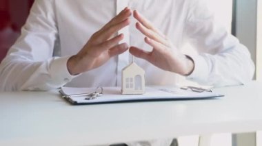 İşadamı kendi elleriyle evi koruyor ve koruyor - mülk ve gayrimenkul sigortası kavramı.