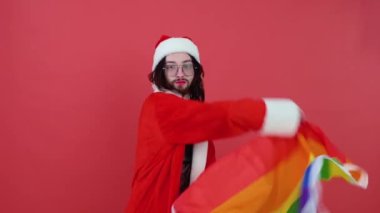 Noel Baba gibi giyinmiş bir adam elinde çok renkli bir bayrak tutuyor.