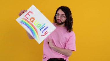 Çekici sakallı beyaz bir adam LGBT geçit töreni sırasında protesto işareti tutuyor. Eşitlik kavramı.