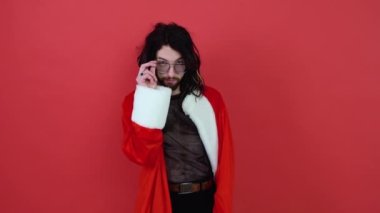 Kırmızı arka planda eşcinsel bir adamın portresi. Noel Baba kostümlü neşeli.