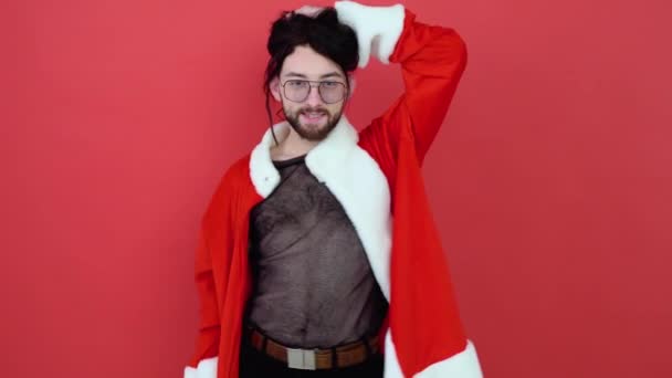 若い笑顔幸せな陽気なゲイの男はメッシュTシャツとクリスマスサンタクローススーツを身に着けている明るい赤の色の背景スタジオの肖像画に隔離された ライフスタイル Lgbtq Prideコンセプト — ストック動画