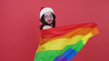 Noel Baba gibi giyinmiş bir adam elinde çok renkli bir bayrak tutuyor.