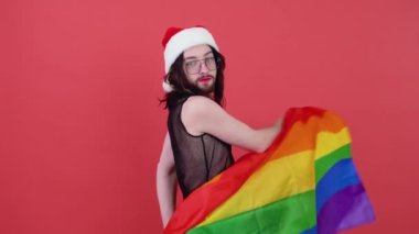 Noel Baba gibi giyinmiş bir adam elinde çok renkli bir bayrak tutuyor.