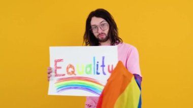 Çekici sakallı beyaz bir adam LGBT geçit töreni sırasında protesto işareti tutuyor. Eşitlik kavramı