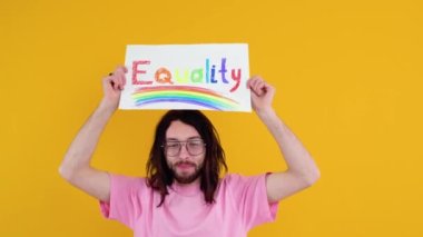 Çekici sakallı beyaz bir adam LGBT geçit töreni sırasında protesto işareti tutuyor. Eşitlik kavramı