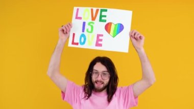 Çekici sakallı beyaz bir adam LGBT geçit töreni sırasında protesto işareti tutuyor. Aşk aşktır.