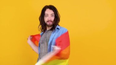 Sarı arka planda Gökkuşağı bayrağı taşıyan adam. Gay gurur konsepti. Homoseksüel aşka oy verin.