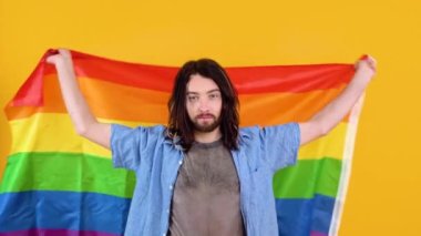 Sarı arka planda Gökkuşağı bayrağı taşıyan adam. Gay gurur konsepti. Homoseksüel aşka oy verin