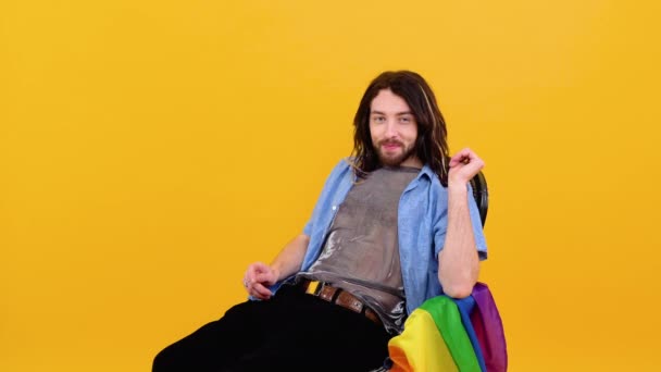 穿着网眼T恤的同性恋者坐在椅子上 椅子上挂着五颜六色的国旗 概念多样性 变性和自由 — 图库视频影像