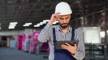 Güvenlik Üniforması ve Sert Şapka Giyen Profesyonel Ağır Sanayi Mühendisi İşçi Tablet Bilgisayar kullanıyor. Ciddi Başarılı Kadın Endüstri Uzmanı Metal Üretim Deposunda Yürüyor.