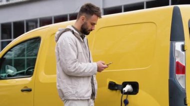 Bir adam şarjlı elektrikli aracın fişini çekti.