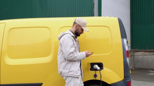 倉庫近くの貨物電気自動車を充電する配達人 — ストック動画