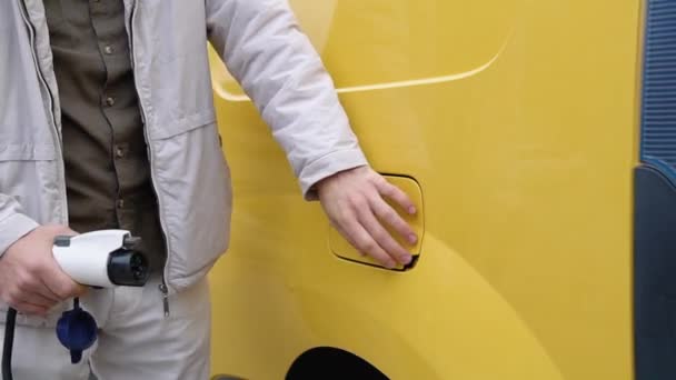 Ein Mann Steckt Ein Ladekabel Ein Elektrofahrzeug Und Lädt Batterien — Stockvideo