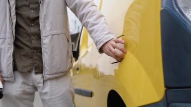 Elektrikli araca kablo bağlayan ve bataryaları şarj eden bir adam. Erkek el kargo EV vagonuna güç bağlantısı yerleştirir