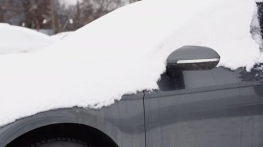 Yakın planda genç bir adam soğuk bir günde kar yağdıktan sonra arabasını temizliyor. Bir kış günü arabayı kardan temizlemek ve temizlemek. Kar yağışı ve kışın şiddetli bir kar fırtınası..