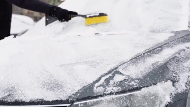 曇り空の日に雪が降った後 車を片付ける青年 冬の日に雪から車を清掃して清掃します 冬の激しい雪嵐 — ストック動画