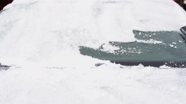 冬の日に屋外の車のフロントガラスから雪を掃除する男 — ストック動画