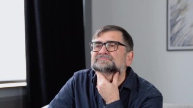 Evde kanepede otururken yaşlı adamın boynuna dokunması sinir bozucu. Boğazında korkunç bir ağrı var.