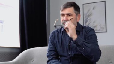 Başı ağrıyan üzgün yaşlı adam boş bir odada tek başına oturuyor..