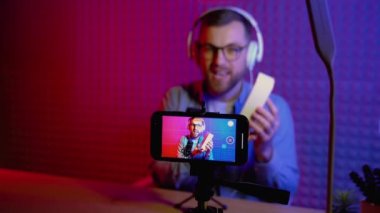 Heyecanlı genç blog yazarı yeni akıllı telefonuyla birlikte kutusunu açıyor ve canlı yayın yapıyor. İçerik yaratmak için akıllı telefon kamerası kullanan çekici bir adam..