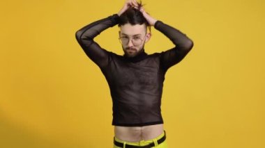 Sarı arka planda izole edilmiş gözlüklü ve örgülü tişörtlü neşeli neşeli genç adam. Yaşam tarzı lgbtq gurur kavramı