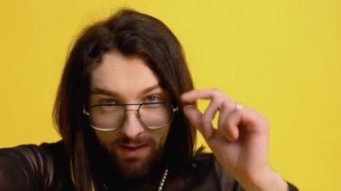 Genç eşcinsel adam sarı arka planda selfie çekiyor..