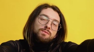 Genç eşcinsel adam sarı arka planda selfie çekiyor.