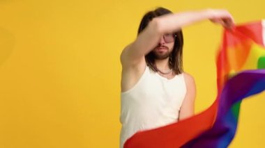 Sarı arka planda Gökkuşağı bayrağı taşıyan adam. Gay gurur konsepti. Homoseksüel aşka oy verin.