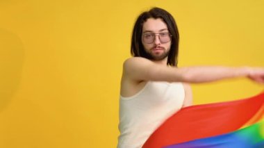 Sarı arka planda gökkuşağı bayrağı taşıyan adam. Gay gurur konsepti