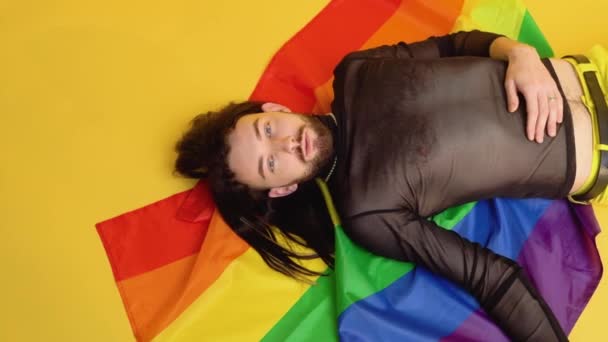 Schwuler Mann Mesh Shirt Liegt Auf Gelbem Grund Mit Regenbogenfahne — Stockvideo