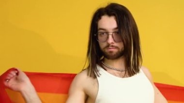 Sarı arka planda Gökkuşağı bayrağı taşıyan adam. Gay gurur konsepti. Homoseksüel aşka oy verin