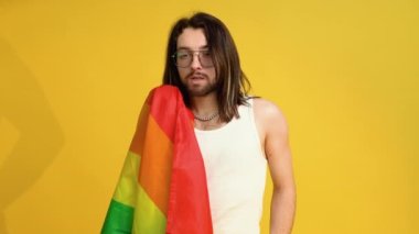 Sarı arka planda Gökkuşağı bayrağı taşıyan adam. Gay gurur konsepti. Homoseksüel aşka oy verin