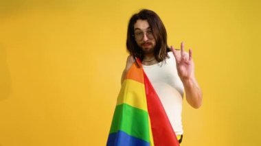 Sarı arka planda Gökkuşağı bayrağı taşıyan adam. Gay gurur konsepti. Homoseksüel aşka oy verin